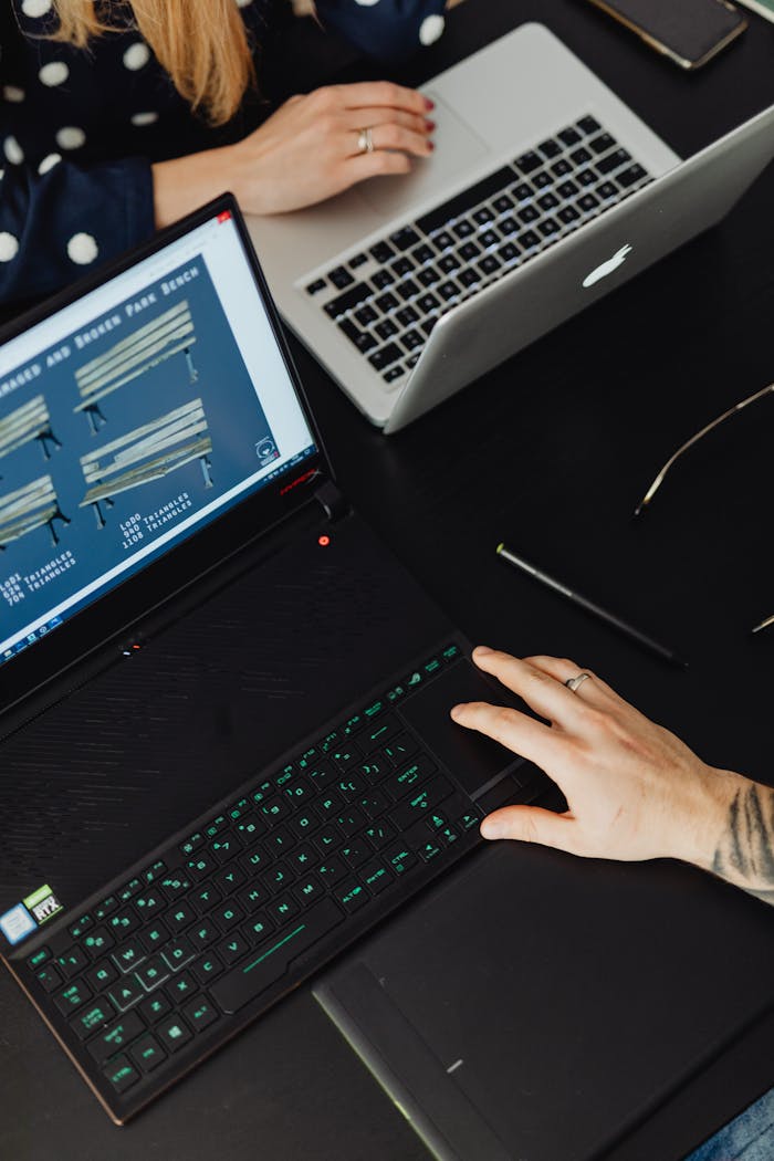 Services-02 Top view of a collaborative workspace with two laptops and hands engaged in activity.